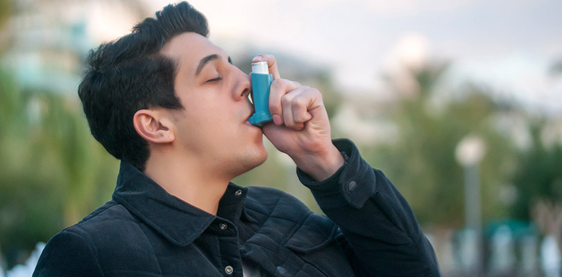 A man is using an asthma inhaler